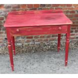 A red painted and parcel gilt side table with raised back, fitted one drawer, on turned supports,