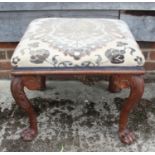 A carved walnut stool with acanthus scroll decoration and lion paw feet, 22" wide x 18" deep x 17"