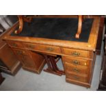 An Edwardian oak double desk with American cloth lined top, fitted nine drawers, on block base,