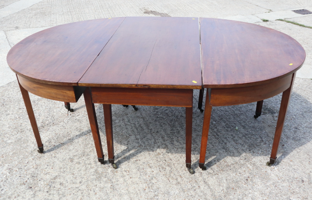 A late Georgian mahogany dining table with centre section, on square taper supports and brass
