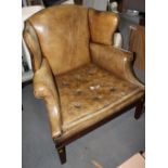 A leather wing armchair of Georgian design, on moulded supports