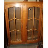 A French carved light oak bookcase, fitted adjustable shelves enclosed two lattice glazed doors,