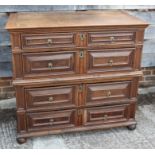 An 18th century oak chest of four long drawers with fielded panel fronts and brass handles, on bun