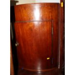 A 19th century plain bowfront mahogany corner cabinet with tray top, 21" wide