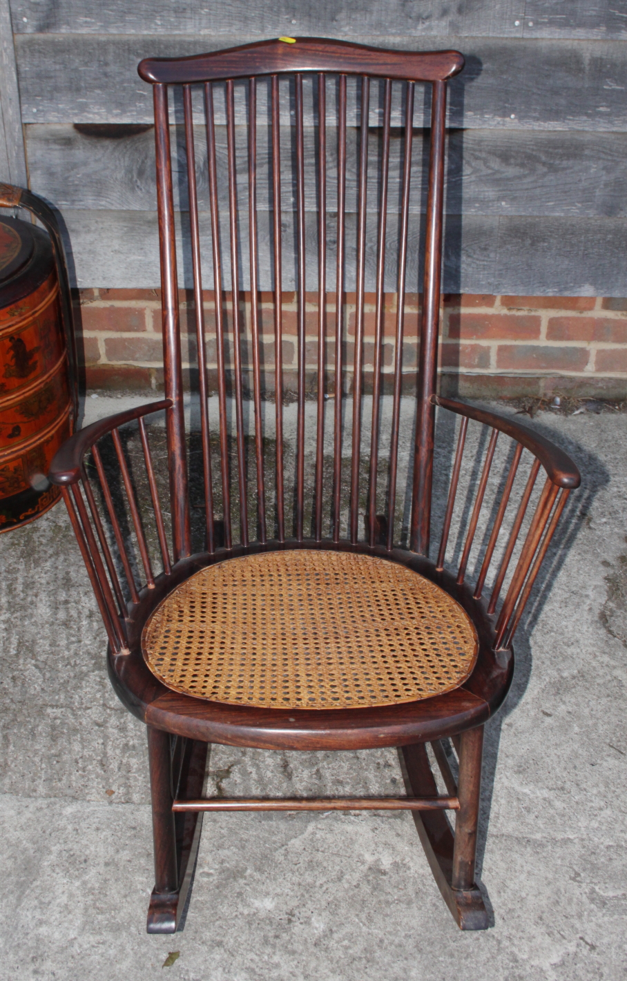 A tall spindle back rocking chair with caned seat panel