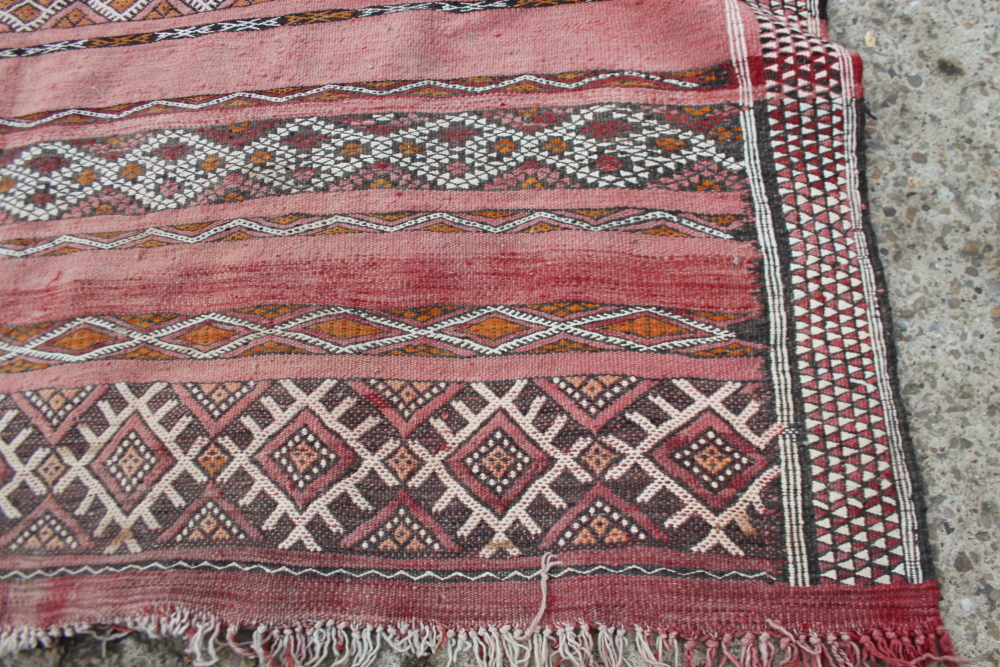 A Moroccan tribal rug decorated bands of geometric ornament on a red ground, 106" x 70" approx - Image 2 of 6