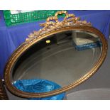 An oval bevelled plate wall mirror, in gilt frame with ribbon surmount, 31" x 34"