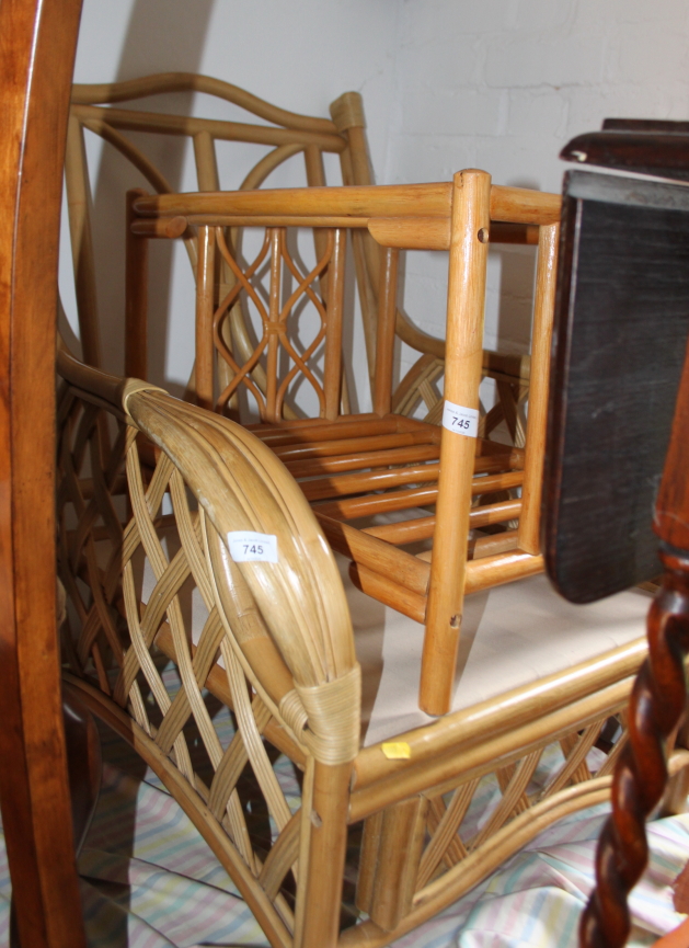 A cane framed garden armchair and a similar glass topped coffee table