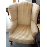 A Georgian design high wing-backed armchair, upholstered in a gold stripe fabric, on carved cabriole