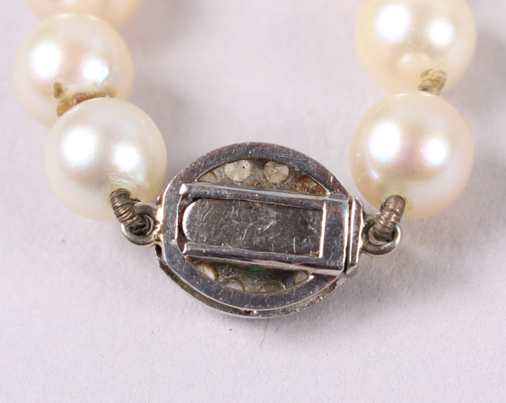 A string of uniform cultured pearls with white metal, diamond and emerald clasp, 14 1/2" long - Image 3 of 3