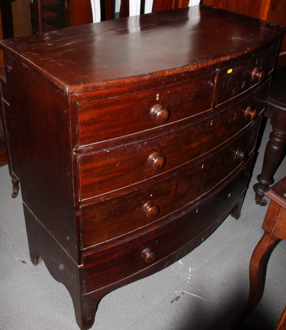 An early 19th century mahogany bowfront chest of two short and three long drawers with turned wooden
