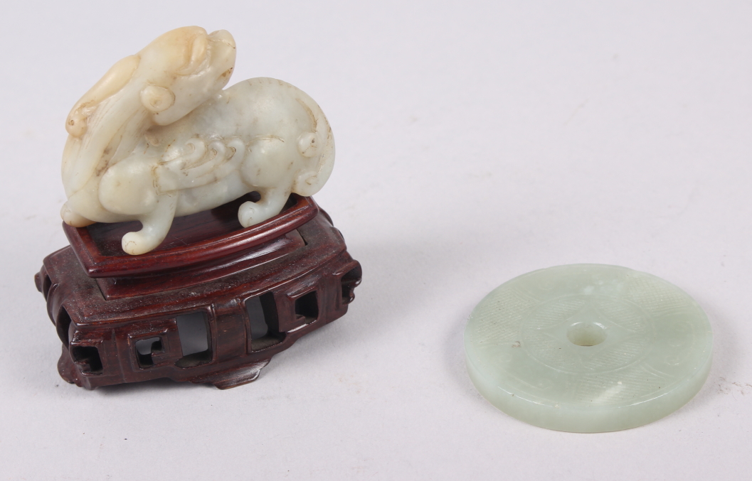 A Chinese carved jade model of a dragon, on hardwood stand, 3 1/4" high overall, and a carved jade
