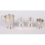 A pair of modern silver pepper mills, a silver egg cup and a silver pedestal christening cup