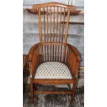 An Edwardian tall spindle back armchair with nailed upholstered seat panel