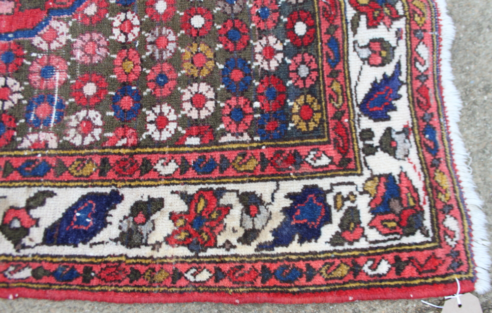 A Persian rug decorated large central medallion on a red floral ground with three border stripes, - Image 2 of 3