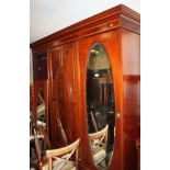 An Edwardian satinwood banded mahogany three-door wardrobe fitted central mirror, 74" wide