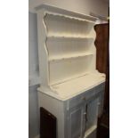 A white painted pine dresser, fitted shelves over two drawers and two cupboards with central recess,