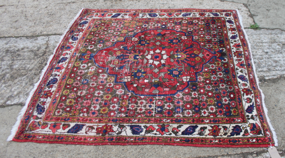 A Persian rug decorated large central medallion on a red floral ground with three border stripes,