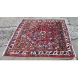 A Persian rug decorated large central medallion on a red floral ground with three border stripes,