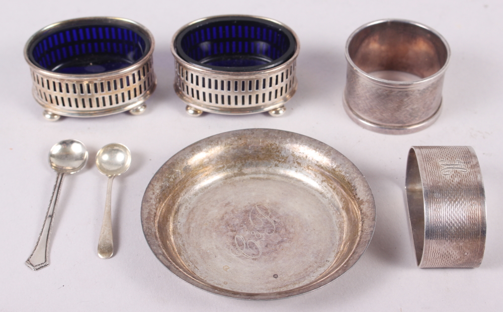 A pair of silver salts with blue glass liners, two silver salt spoons, a silver pin dish and two