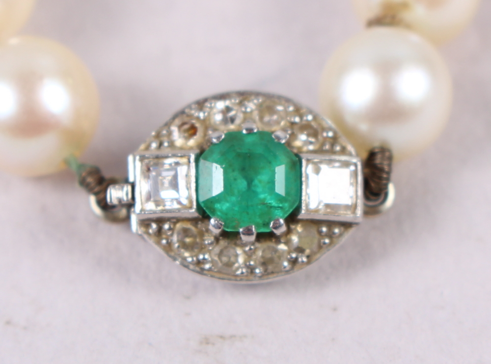 A string of uniform cultured pearls with white metal, diamond and emerald clasp, 14 1/2" long - Image 2 of 3