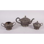 An Oriental white metal three-piece teaset with embossed decoration, 30.7oz troy approx (dent to