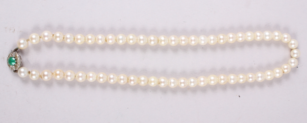 A string of uniform cultured pearls with white metal, diamond and emerald clasp, 14 1/2" long