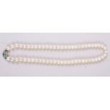 A string of uniform cultured pearls with white metal, diamond and emerald clasp, 14 1/2" long