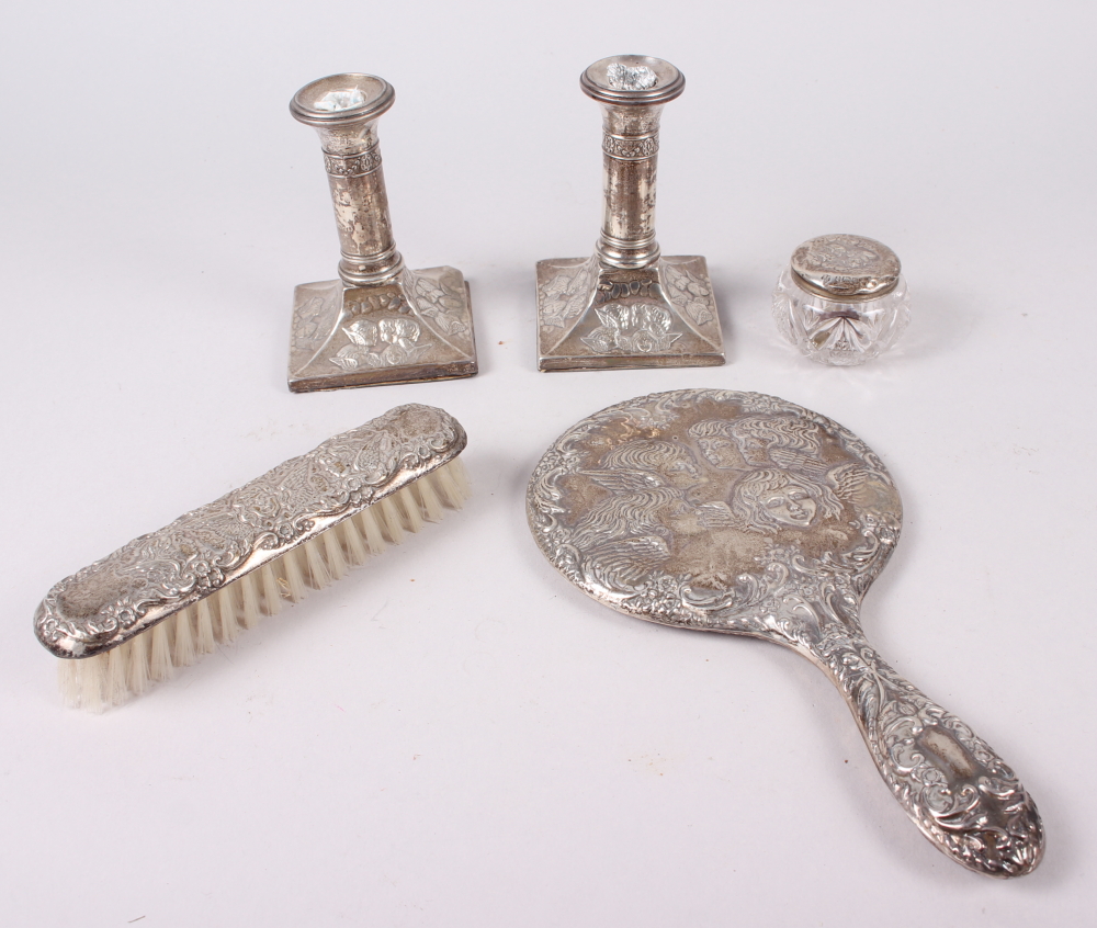 A pair of squat silver candlesticks embossed cherubs' heads, and a similar hand mirror, pin jar