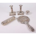 A pair of squat silver candlesticks embossed cherubs' heads, and a similar hand mirror, pin jar