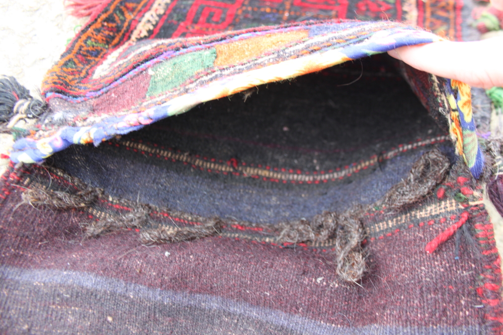 A Caucasian saddle bag decorated square hooked medallion on a red ground, 32" x 15" approx - Image 2 of 3