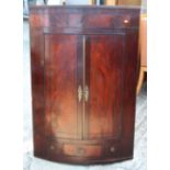 A Georgian bowfront mahogany corner cabinet inlaid ebony stringing, 33" across