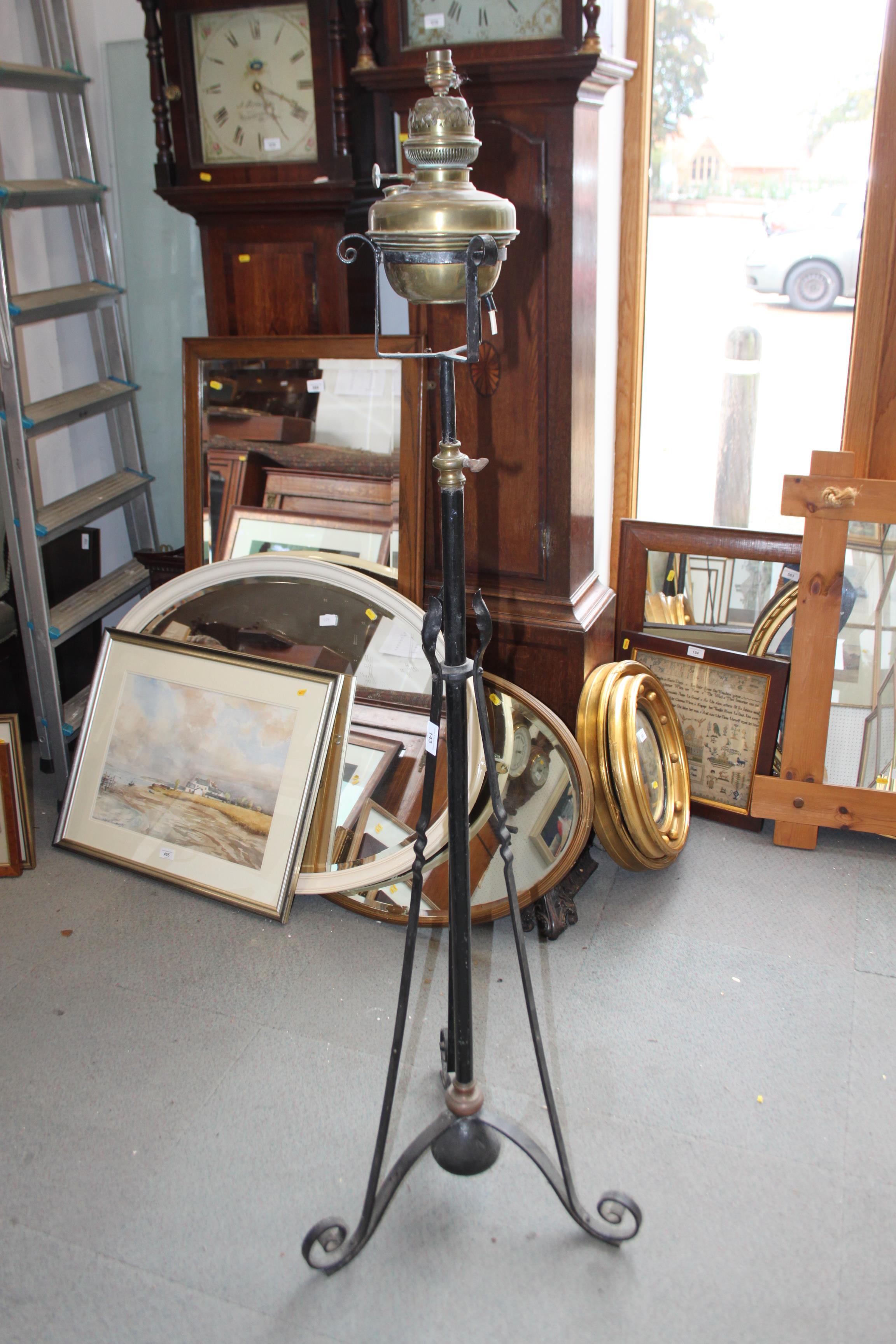An Edwardian brass oil lamp, on black metal stand with tripod base