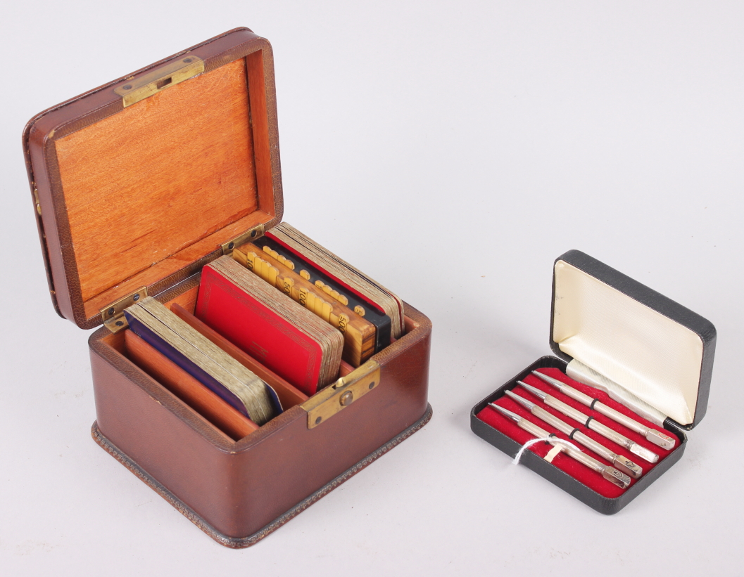 A leather playing card box, two bezique markers, a cased set of four sterling silver bridge