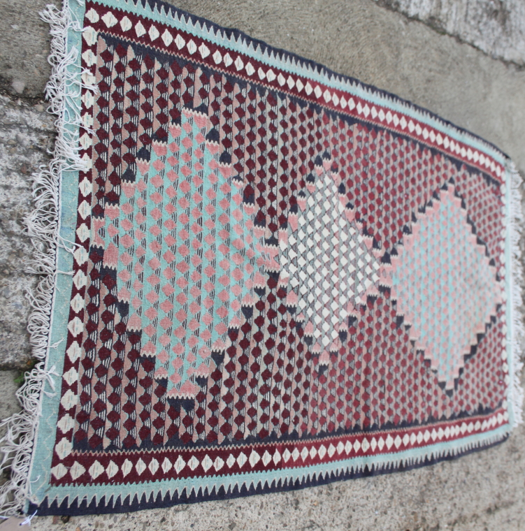A kelim rug decorated three lozenges on a red ground, 70" x 45" approx
