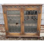 A carved oak bookcase enclosed leaded glazed doors, on stile supports, 37" wide x 11" deep x 36"