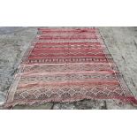 A Moroccan tribal rug decorated bands of geometric ornament on a red ground, 106" x 70" approx