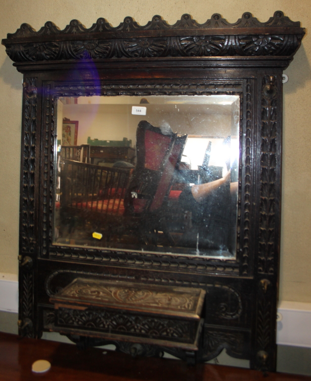 A late 19th century wall mounted hallstand, in heavily carved frame, fitted mirror and glove box,