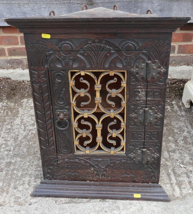 A 19th century carved oak corner cupboard, inscribed RTP 1883, with wrought iron grille door, 20"