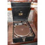 An HMV portable gramophone, in black case, and a brown leather suitcase