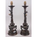 A pair of Chinese bronze table lamps with relief dragon decoration, on circular bases, 17 1/2" high
