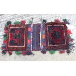A Caucasian saddle bag decorated square hooked medallion on a red ground, 32" x 15" approx