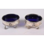 A pair of George III oval silver salts with pierced sides engraved swags, on ball and claw supports,