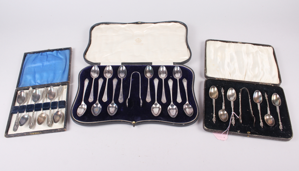 A cased set of six silver apostle teaspoons with matching tongs and two other silver plated sets