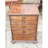 A 19th century mahogany bedside chest of five long graduated drawers with drop leaf back, on bun
