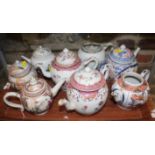 A Chinese export teapot with floral decoration and pink borders, and seven other teapots