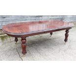 A mahogany extending dining table of mid 19th century design with two extra leaves, on tulip