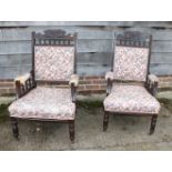 A pair of late Victorian open armchairs, upholstered in a floral fabric, on turned supports