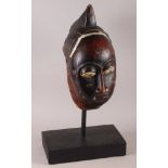 A West African carved hardwood tribal mask, on ebonised stand, 13 1/4" high