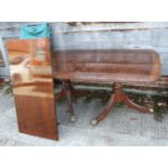 A mahogany and banded extending two pedestal dining table with one extra leaf, on splayed